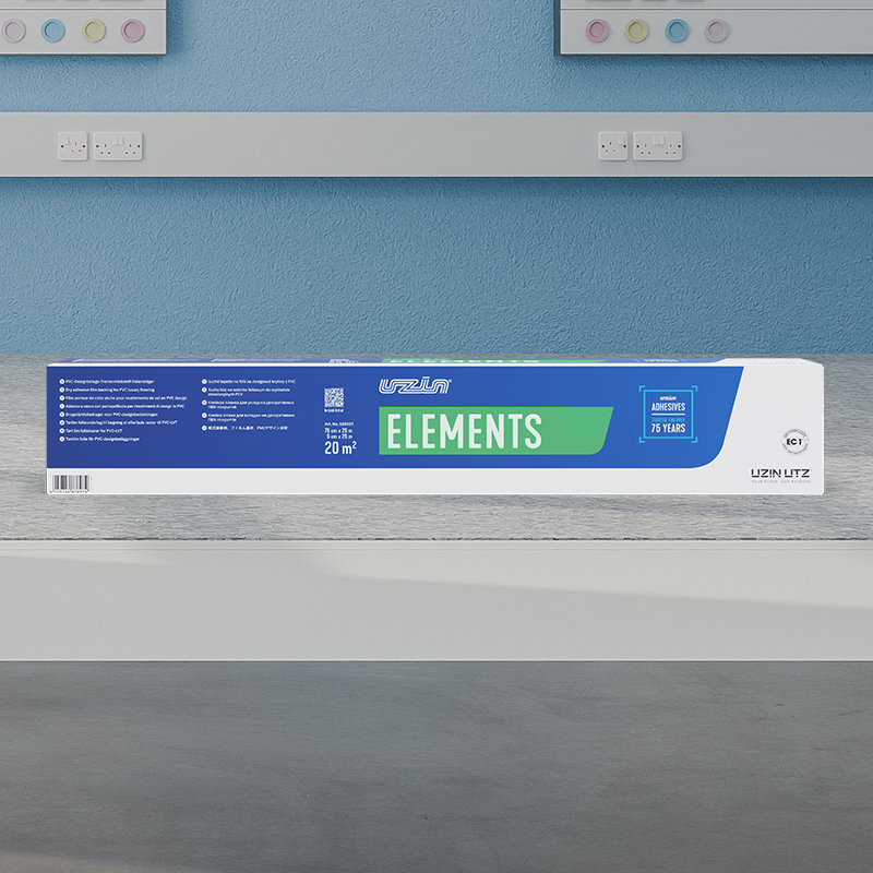 Eine lange rechteckige Schachtel Trockenklebstoff mit der Aufschrift UZIN ELEMENTS steht auf einem Tisch in einem hell erleuchteten Raum mit blauen Wänden und Steckdosen im Hintergrund. Die Schachtel ist hauptsächlich blau und weiß mit grünen Akzenten.