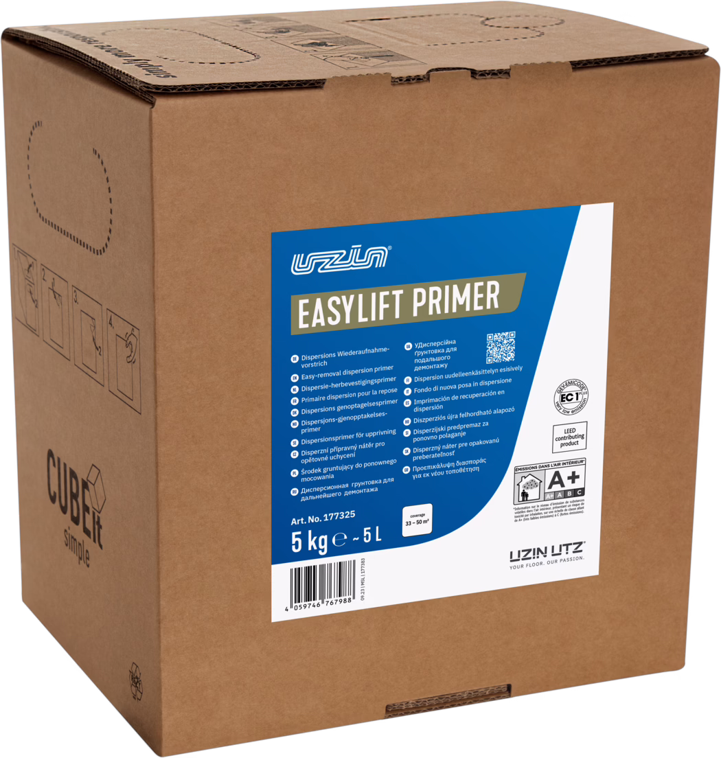 UZIN_Dummy_EasyLift Primer-5kg_2023-09 Fotografie eines großen braunen Wellpappkartons, der aufrecht steht und auf der Vorderseite ein auffälliges blau-weißes Produktetikett mit der Aufschrift 'EASYLIFT PRIMER' trägt. Das Etikett zeigt das UZIN-Logo, technische Symbole, einen Barcode sowie die Mengenausweisung '5 kg ≈ 5 L' und beschreibt das Produkt als Dispersions-Primer für die Bodenvorbereitung. Der Karton verfügt über ausgestanzte Tragegriffe an den Seiten, gedruckte Montage- und Handhabungspiktogramme, ein kleines 'CUBEit simple'-Logo auf der linken Seite und gefaltete Klappen oben; die Kraftpapieroberfläche zeigt die natürliche Papierstruktur. Das Bild konzentriert sich auf die Verkaufsverpackung und bietet eine klare Ansicht von Etiketttext und Prüfzeichen (unter anderem eine A+ Innenraum-Emissionsklasse) und präsentiert die Verpackung als für Bodenleger und Bauelemente-Profis konzipiert.