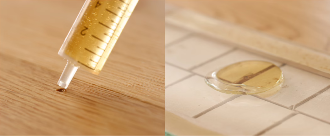 Nahaufnahme im Diptychon, die einen gelblich-braunen Klebstoff zeigt, der aus einer Spritze abgegeben wird: links bildet sich ein kleiner Tropfen auf einer Holzoberfläche, rechts liegt ein runder Klebstofftropfen auf weißen Keramikfliesen mit einem teilweise eingesetzten runden Holzstopfen. Warmes Licht betont die Holzmaserung und die Fugen; geringe Schärfentiefe macht den Hintergrund weich, während die Markierungen auf der Spritze und die Struktur des Klebstoffs sichtbar bleiben.