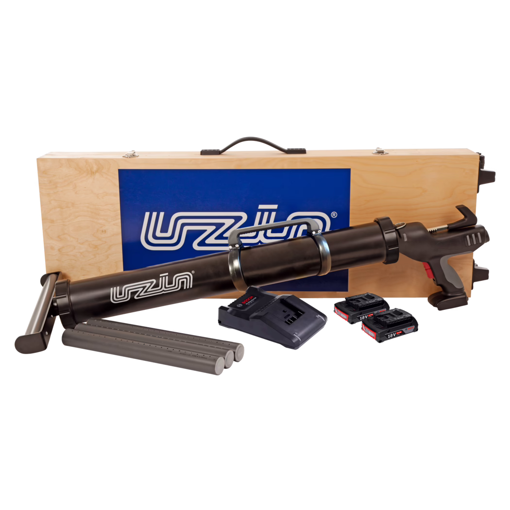 Holzkoffer mit schwarzem akkubetriebenem Kartuschen- und Klebepistole sowie Zubehör: Im Hintergrund ist die Oberseite eines hellen Sperrholzkoffers mit schwarzem Griff und blauem Logopanel zu sehen, davor eine lange schwarze, akkubetriebene Kartuschenpistole. Vor dem Koffer liegen drei graue Kartuschenrohre, eine Ladegerät-Basis und drei 18V Lithium-Ionen-Akkupacks. Die Pistole verfügt über einen Pistolengriff mit grauen und roten Akzenten, Metallbandspannungen, die das Patronenrohr halten, sowie einen Abzugsmechanismus. Studioaufnahme auf weißem Hintergrund.